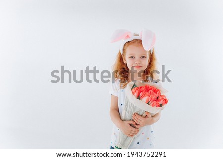 Funny curly girl with bunny ears and flowers on isolated background. Easter holiday concept	