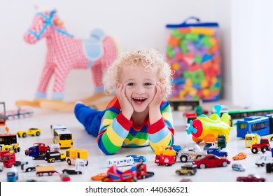 Funny Curly Toddler Boy Playing With His Model Car Collection On The Floor. Transportation And Rescue Toys For Children. Toy Mess In Child Room. Many Cars For Little Boys. Educational Games For Kids.