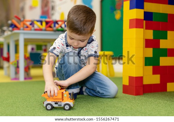 Funny curly toddler boy playing with his model car\
collection on the floor. Transportation and rescue toys for\
children. Toy mess in child room. Many cars for little boys.\
Educational games for\
kids.