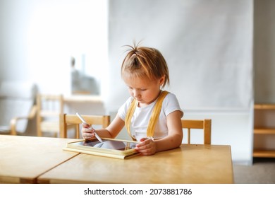 Funny Cute Baby Girl Toddler With Tablet, Child And Gadget. Early Development And Drawing On The Screen, The Child Plays And Learns On The Tablet