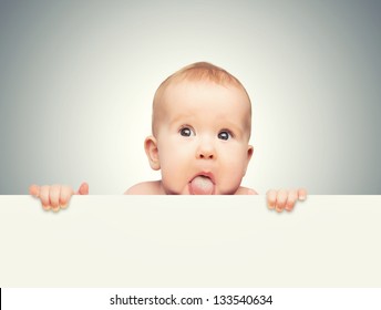 funny cute baby with white blank banner in hand isolated on a gray background