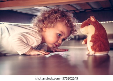 Funny Cute Curious Baby Playing Under The Bed With Toy Hamster In Vintage Style