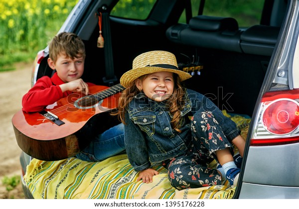 funny cute kids in the trunk of the car . Children\
play in the car in nature