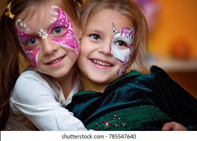 Funny cute little girls with painting faces are hugging ang having fun.