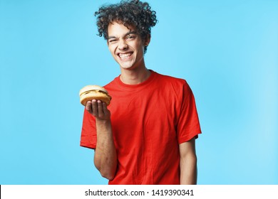 Funny cute man hamburger in the hands of a red T-shirt fast food blue background