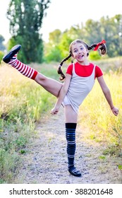 A funny cute outdoor portrait of a little girl presenting Pippi Longstocking and showing out out her tongue. 