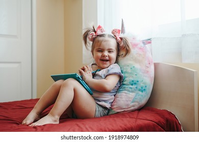 Funny Cute Smiling Toddler Baby Girl Drawing With Stylus On Digital Drawing Pad Tablet. Little Kid Child Using Technology. Early Age Education Development. Happy Authentic Home Lifestyle Childhood.