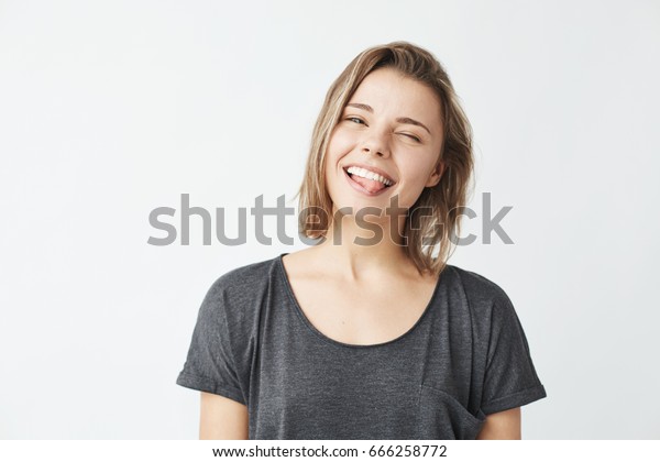 白い背景にカメラを見ながら舌をまばたかせながら笑う可笑しい可愛い若い女の子 の写真素材 今すぐ編集