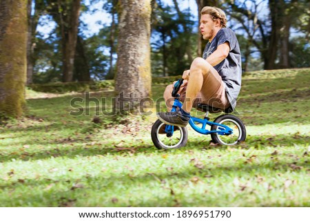 Funny downhill on small kids balance bike. Young crazy man riding down from high hill.