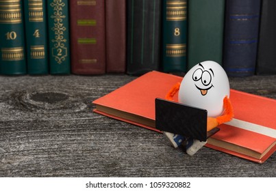 Funny Easter egg with notebook computer sitting on a book in a library. Education concept.