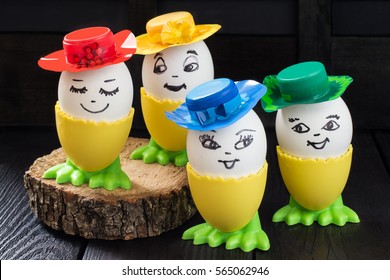 Funny Easter Eggs With A Smile On The Face In Handmade Colorful Hats On A Dark Wooden Table. DIY Concept. Children's Art Project