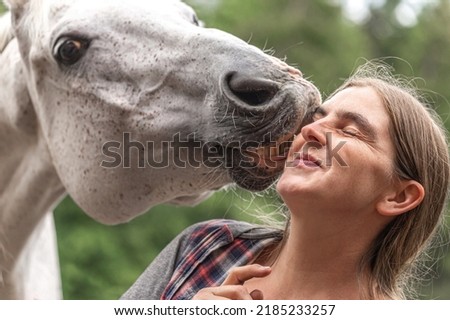 Funny equestrian team scene: A horse showing a kissing trick on command. Horse and owner having fun and joy