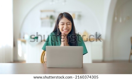 Funny euphoric young asian woman celebrating winning or getting ecommerce shopping offer on computer laptop. Excited happy girl winner looking at notebook celebrating success