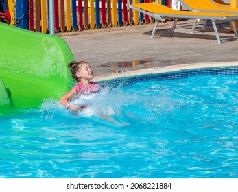 A Funny Excited Kid Enjoying Summer Vacation On The Waterslide At The Hotel's Water Park.