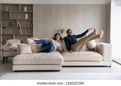 Funny excited millennial spouses of new homeowners falling on big soft couch at home. Young couple celebrating moving into first common house. Real estate, renovation, furniture for hoe concept - Shutterstock ID 2182327281