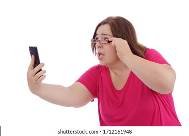 
Funny And Expressive Overweight Woman With Presbyopia Having Trouble Reading Her Messages On Her Smartphone With Her Glasses On White Isolated Background