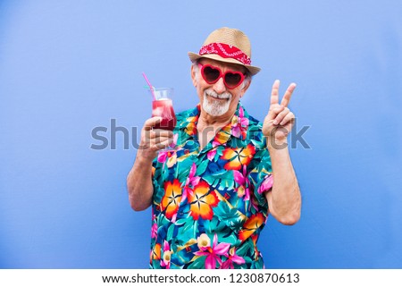 Funny and extravagant senior man posing on colored background - Youthful old man in the sixties having fun and partying