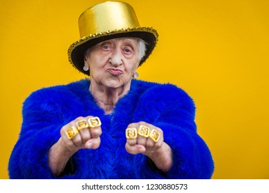 Funny and extravagant senior woman posing on colored background - Youthful old woman in the sixties having fun and partying