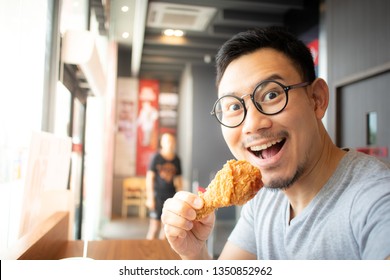 Funny Face Of Asian Man Eat Fried Chicken In The Franchise Cafe.