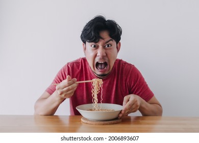 Funny Face Of Asian Man Eat Very Hot And Spicy Instant Noodle.