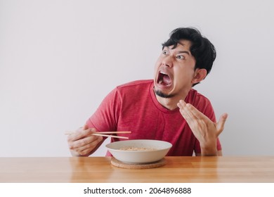 Funny face of Asian man eat very hot and spicy instant noodle.