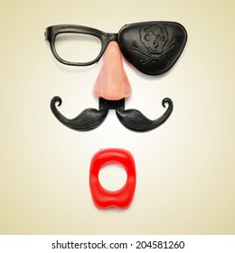 a funny face formed with fake mouth, nose and glasses with mustache and pirate patch on a beige background, with a retro effect