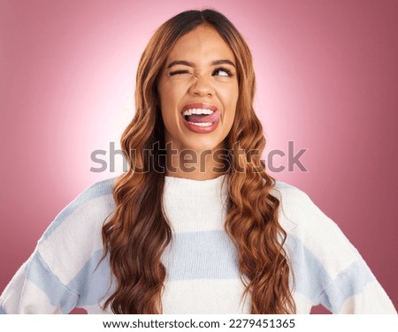 Funny, face and goofy woman tongue out feeling happy, playful and excited isolated in a studio purple background. Comic, joke and head of a young and crazy female wink for humor or happiness