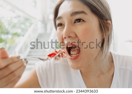 Funny face of happy asian woman eating cake carelessly in the cafe.