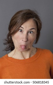 Funny Face For Happy Middle Aged Woman With Eyes Wide Opened, Tongue Stuck Out The Mouth For Goofy And Playful Effects, Grey Background