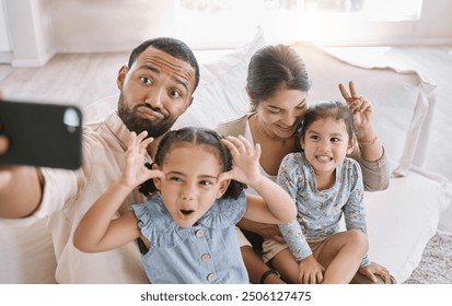 Funny face, love and selfie with family on sofa in living room of home together for bonding or humor. Bunny ears, happy or relax with mom, dad and sibling girl children in apartment for photograph - Powered by Shutterstock