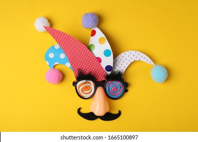 Funny face made of party items on yellow background, flat lay. April Fool's Day