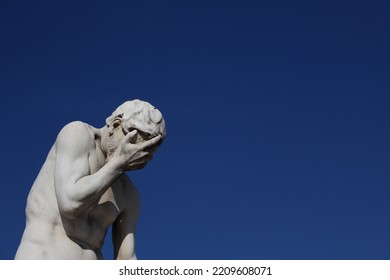 Funny face palming statue background with copy space. Concept for frustration, failure, annoyance. Statue labelled Cain coming from killing his brother Abel (Tuileries Garden, Paris, France)