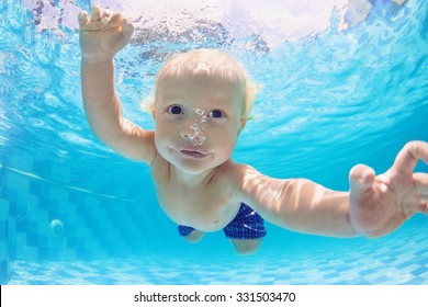 Funny Face Portrait Of Little Baby Boy Swimming And Diving Underwater With Fun In  Pool. Active Healthy Lifestyle, Water Sport Activity And Lessons With Parents On Summer Family Vacation With Child.