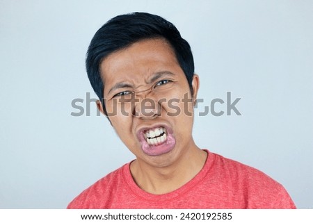 funny facial of asian man surprised and dumbfounded, he looks at the camera grimacing his mouth