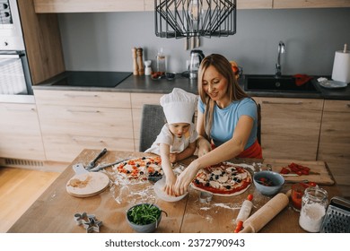 Funny family daughter and mother making pizza for dinner at the kitchen. Happy family together. - Powered by Shutterstock