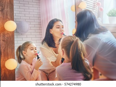 Funny Family At Home. Mother And Her Child Girl Are Doing Your Makeup And Having Fun Near Mirror. Mom And Daughter Wear Lipstick In Kids Room.