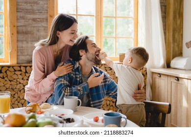 Funny family moments together. Morning breakfast with parents and little toddler kid child infant feeding father with cake at home kitchen. Parenthood and adoption - Shutterstock ID 2118883274