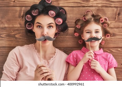 Funny family! Mother and her child daughter girl with a paper accessories. Beauty funny girl holding paper mustache on stick. Beautiful young woman holding paper mustache on stick. - Powered by Shutterstock