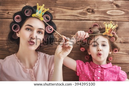 Funny family! Mother and her child daughter girl with a paper accessories. Beauty funny girl holding paper crown on stick. Beautiful young woman holding paper crown on stick.
