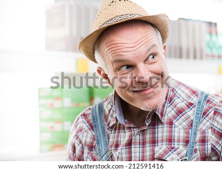 Funny farmer at supermarket making a face and looking around.