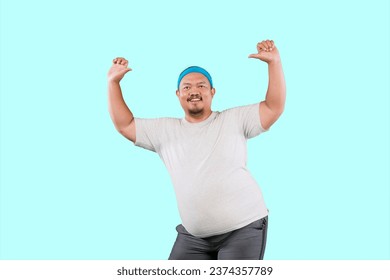funny fat Asian man in white t-shirt smiling and dancing happily, joyful expressing celebrating good news