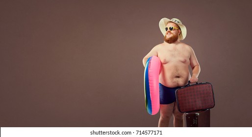 Funny fat bearded man with a suitcase in a hat and glasses on va