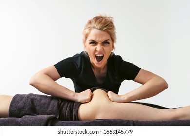 Funny fat burning massage. Portrait of cheerful woman masseur in uniforme near massage table with woman patient in wellness center. White background isolated