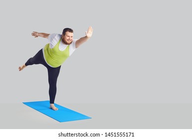 A Funny Fat Man Does Yoga Exercises On A Mat On A Background.