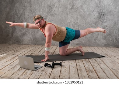 Funny Fat Man In Sports Clothes Doing Exercises. He Plays Sports Remotely While Looking At His Laptop