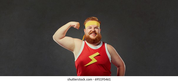 Funny Fat Man In Sports Clothes Shows A Hand With Muscles Biceps