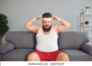 Funny Fat Man In Sportswear Is Sitting On The Sofa In The Room