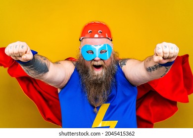 Funny fat man with superhero costume acting as superhuman with special powers, portrait on colored background