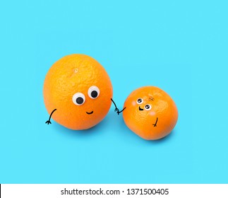 Funny Food - Two Tangerines, Small And Big, On Blue Background. Symbol Of Baby And Parent. Tangerines With Smile And Eyes, Friendly Faces. Creative Idea, Minimal Kawaii Style