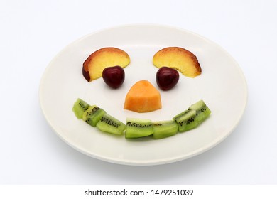 Funny fruit face on a plate as fruity smiley. White background, copy space.